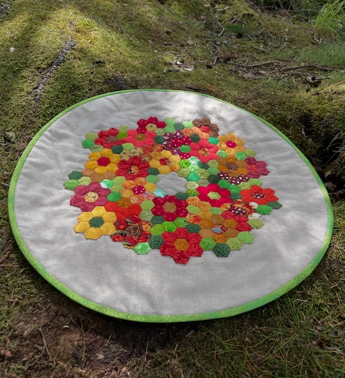 Rund dug med håndsyet blomster i 6 kanter.