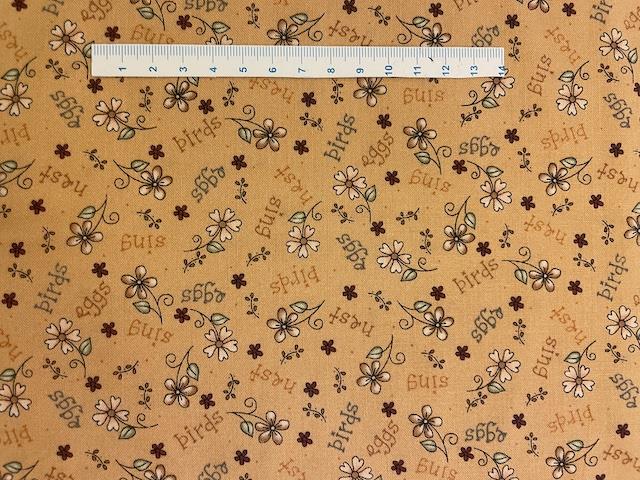 Gult patchworkstof med tekst og blomster