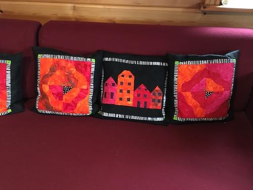 Hej Hanne  Jeg vil selvfølgelig gerne vinde konkurrencen - hvem vil ikke det? Derfor har jeg fundet et par bidrag frem.  Det første er et billede af mit svenske hus. Jeg syede billedet på et kursus hos Betina Andersen for en del år siden. Meget af billedet er håndsyet.  Det næste billede er en sofapude, der er inspireret af Bernadette Mayr. Hun har ingen opskrifter i sine bøger, men opfordrer til, at man designer sit motiv selv. Det har jeg så gjort. Det er blevet til en pude i en serie med andre designs i de sammen farver.  Mange hilsner  Lene Jørgensen 