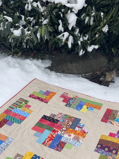 5. del af Resteræs  Nu skal du have dit tæppe samlet med mellemfoer og bagsidestoffet. Når ud har håndsyet dit tæpper - er der flere måde at afslutte dit tæppe på. Jeg har brugt denne metode, dog kun klippet mit mellemfoer 1 cm større og bagside stoffet 3 cm større end mellemforet.